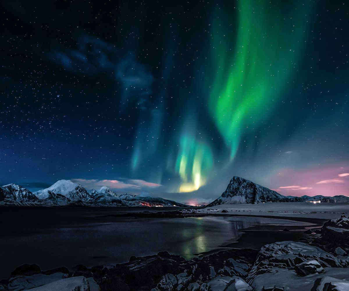 Aurora boreal sobre montanhas nevadas